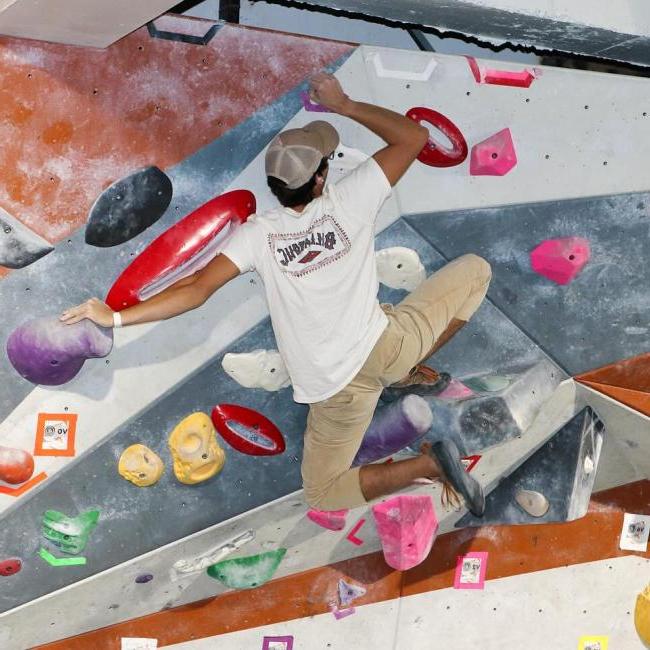 student on the bouldering wall, with club t-shirt on 